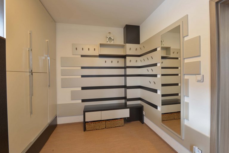 Pohled na rohovou věšákovou stěnu. Kvůli dětem jsou věšáčky v různých výškách, aby si děti mohli oblečení zavěsit sami. 