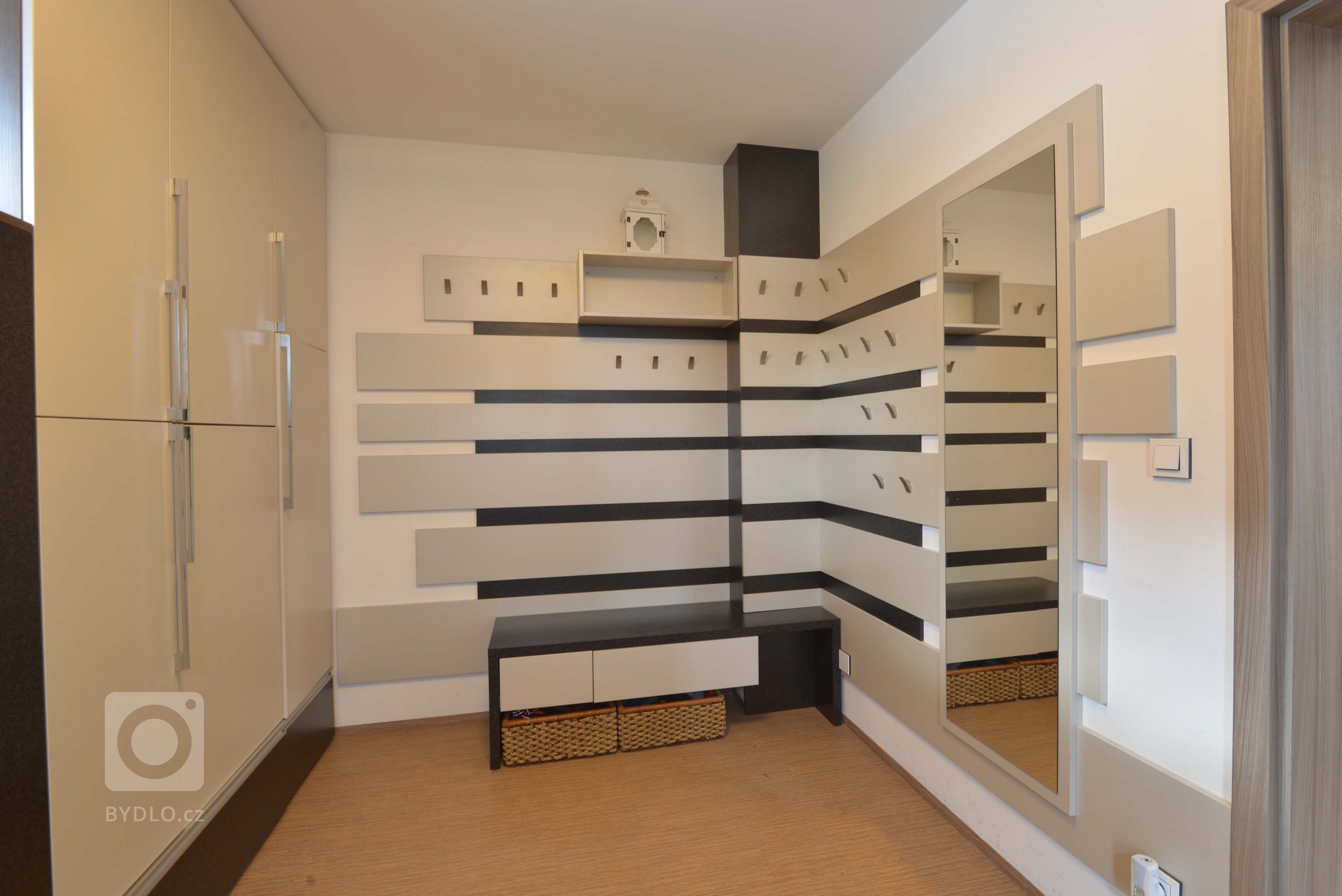 Pohled na rohovou věšákovou stěnu. Kvůli dětem jsou věšáčky v různých výškách, aby si děti mohli oblečení zavěsit sami. 