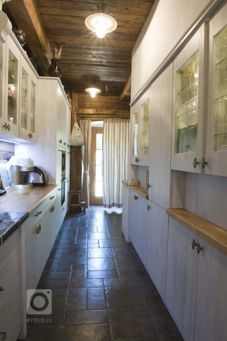 Tmavošedá keramická dlažba se světlým dřevěným odstínem kuchyňského nábytku