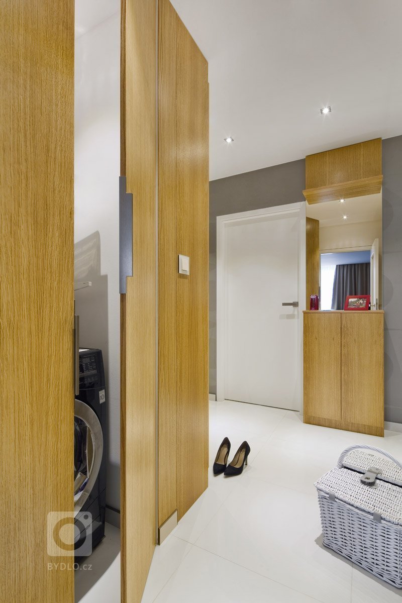 Rekonstrukce panelového bytu v odstínech dřeva a bílé.
