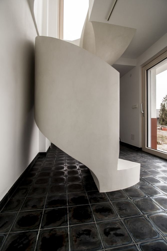 Betonová litá schodiště zpravidla vyžadují opravné úpravy povrchu, které se řeší stěrkou. Stěrka může však být použita na schodišti i k samotnému dekorování, jako například u tohoto bílého schodiště s moniérkou. Stěrkování schodiště vyžaduje precizní práci v hranách a velký smysl pro detail.