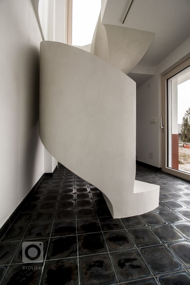 Betonová litá schodiště zpravidla vyžadují opravné úpravy povrchu, které se řeší stěrkou. Stěrka může však být použita na schodišti i k samotnému dekorování, jako například u tohoto bílého schodiště s moniérkou. Stěrkování schodiště vyžaduje precizní práci v hranách a velký smysl pro detail.