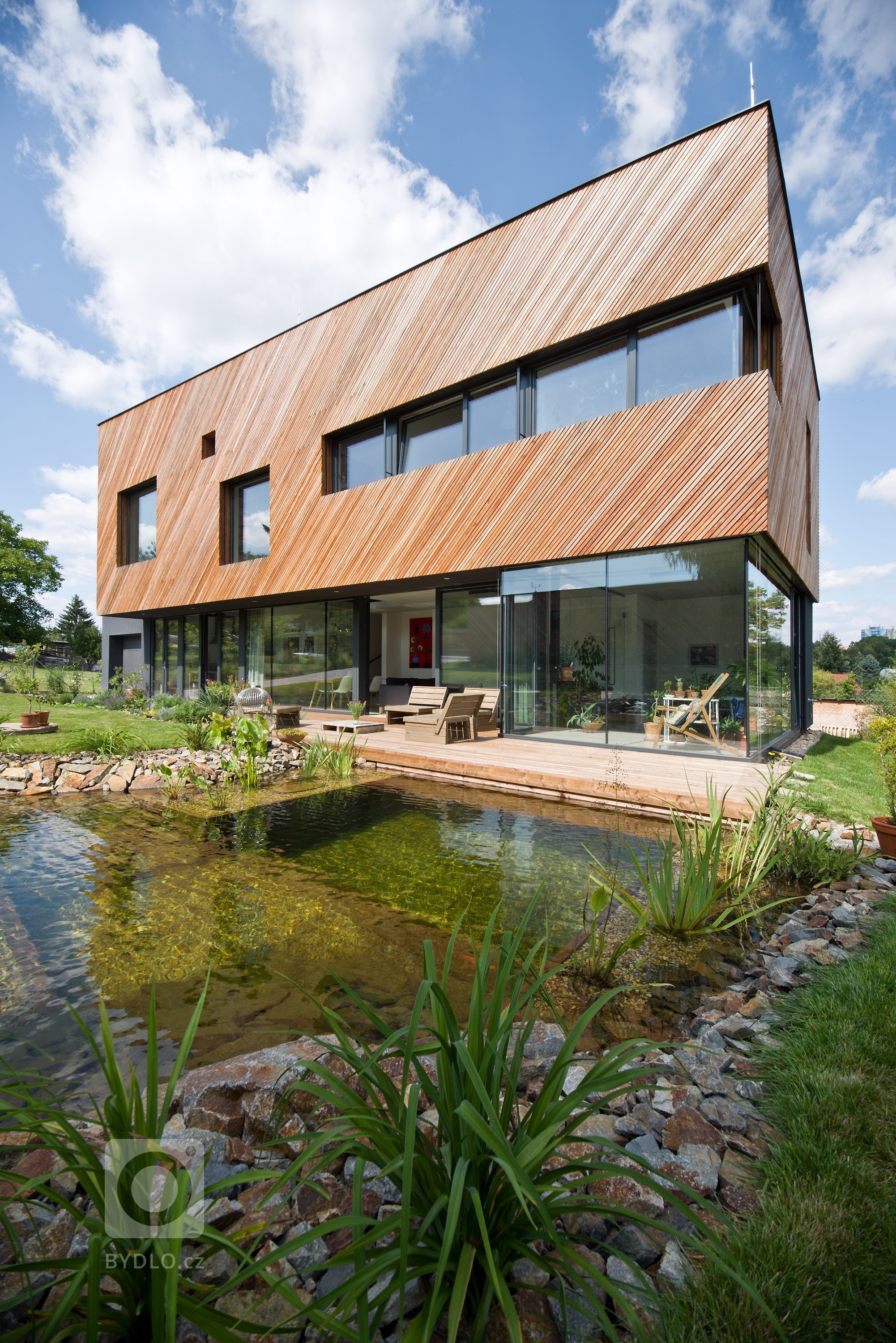Architektonické řešení navazuje na zahrádkářskou minulost parcely a koncept projektu řadových domů. Protáhlá obdélníková stavba má plně prosklené přízemí, na…