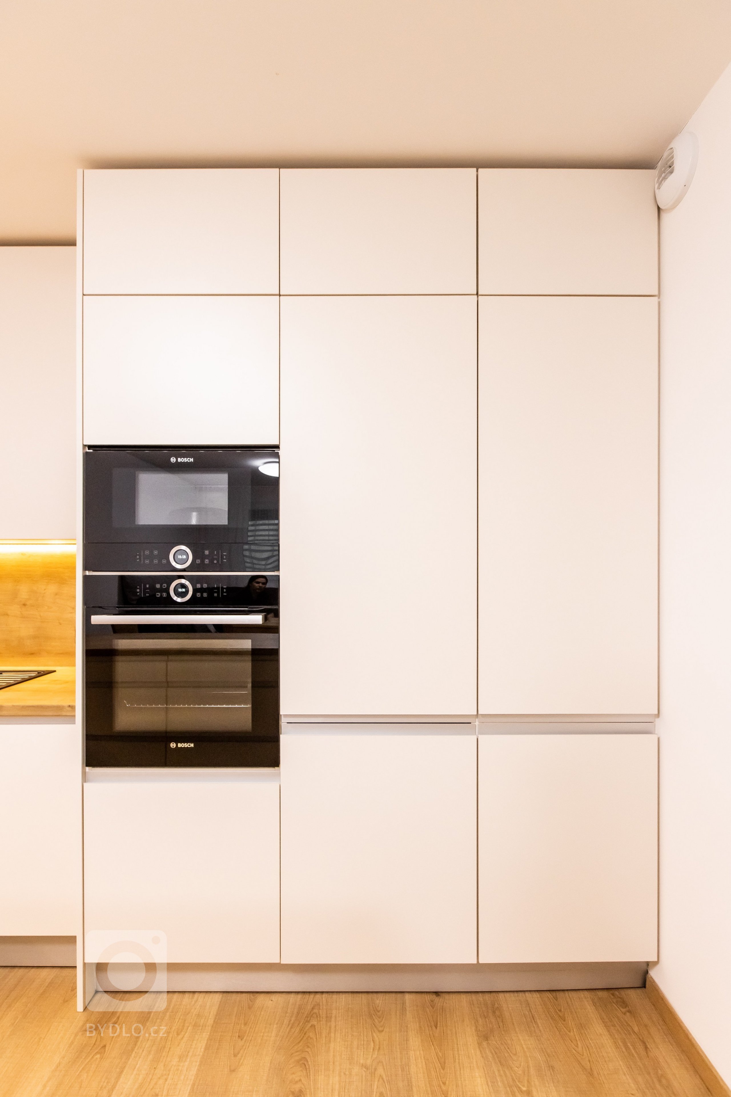 Materiály: Biely perleťový mat a Dub zlatý

Podsvietenie: Teplý&nbsp;LED pás

Madlá: Kuchyňa - Zafrézované hliníkové

Skrine - Madlo v tvare &quot;L&quot…