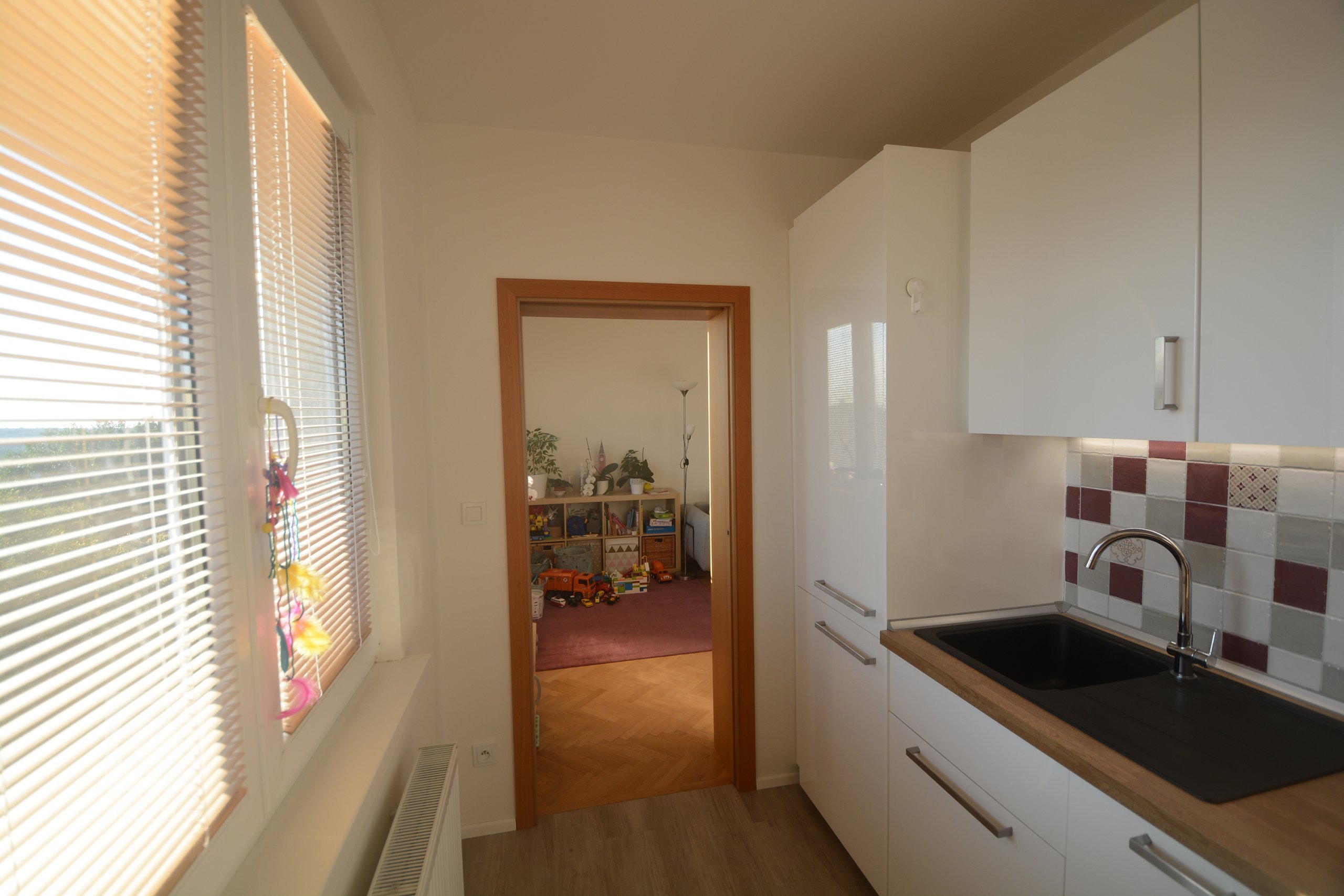 Průhled z kuchyně do dětského hracího koutu a obývacího pokoje s jídelnou