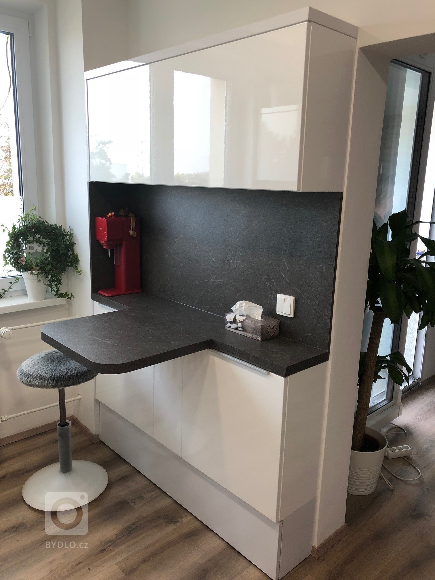 Kuchyňká linka v bílém vysokém lesku s grafosklem, osazená spotřebiči Bosch a doplněná příruční&nbsp;stolovou deskou zabudovanou do skříňkové sestavy…