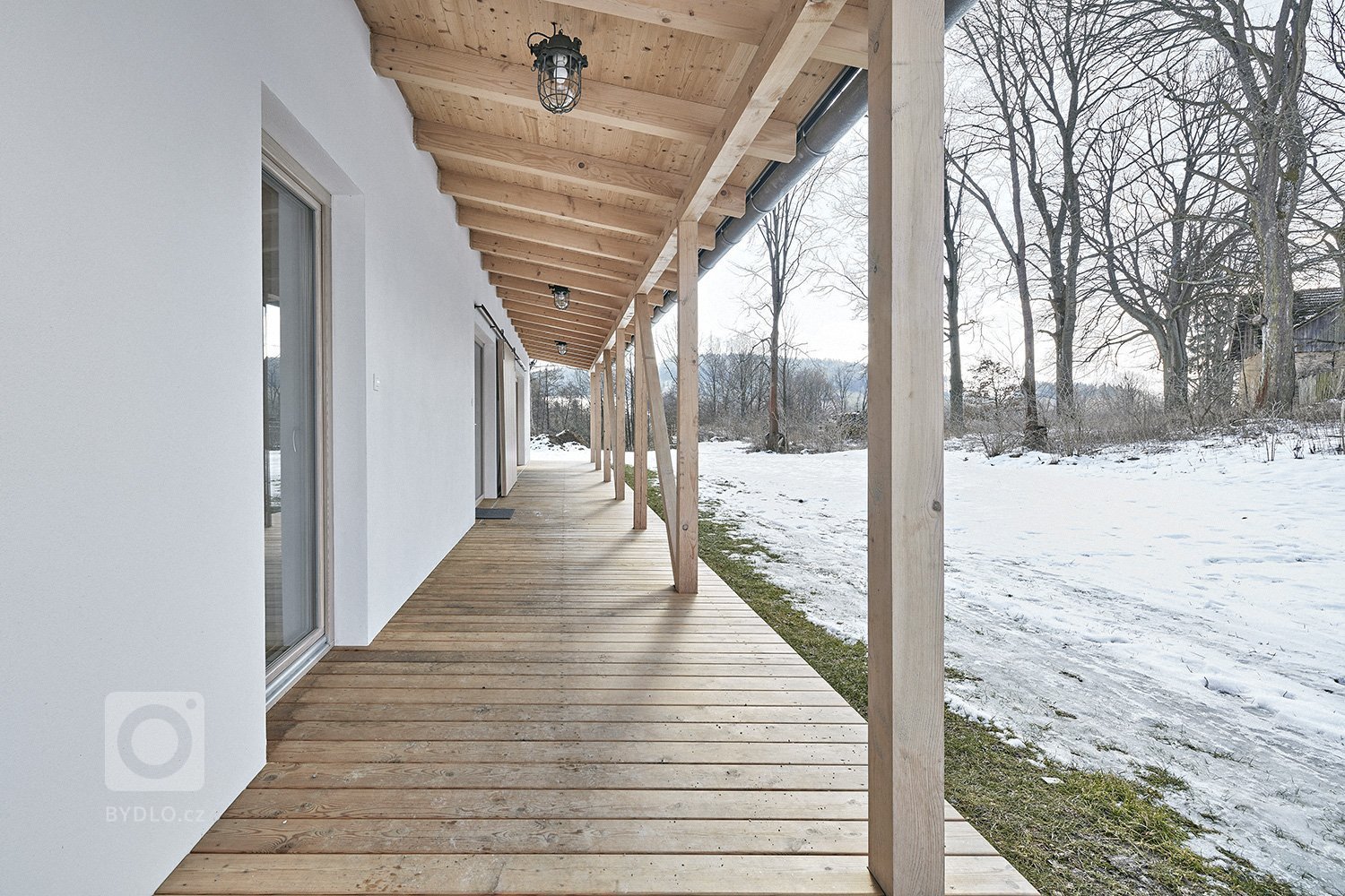 Pozemek leží na hraně svahu v&nbsp;centru malé obce na Vysočině. Na půdorysné stopě bývalého statku vznikl dům a stodola. Dům má podél jihozápadní fasády kryté…