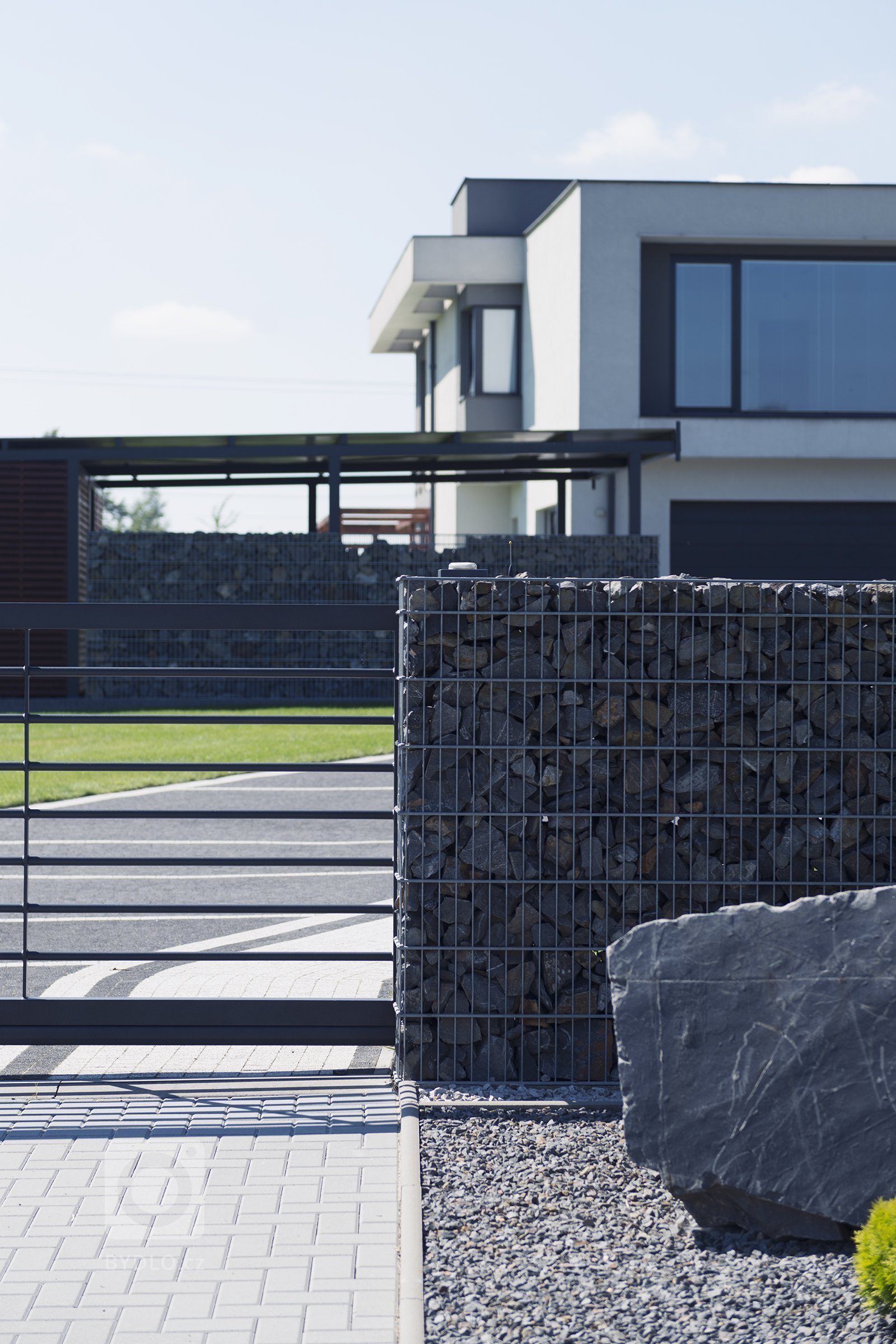 Vjezd v designu Airy, kombinovaný s gabiony Rock (rodinný dům, Orlová).

Funkcionalisticky pojatý dům, kde se slušelo nechat prostor okolo dýchat. Navrhli…