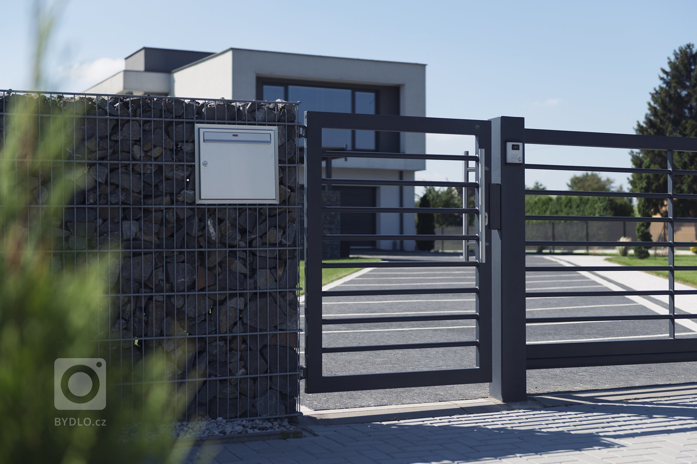 Vjezd v designu Airy, kombinovaný s gabiony Rock (rodinný dům, Orlová).

Funkcionalisticky pojatý dům, kde se slušelo nechat prostor okolo dýchat. Navrhli…