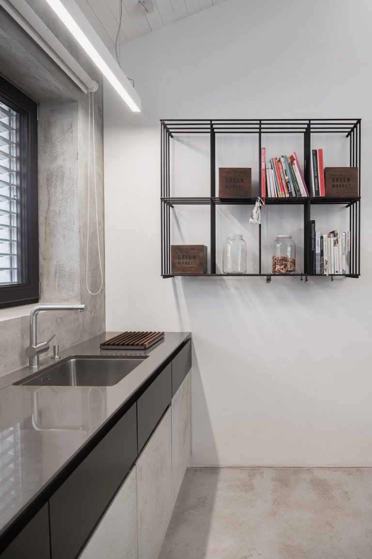 Policová sestava z ocelových prutů je elegantním protikladem k masivní železobetonové kuchyni. 