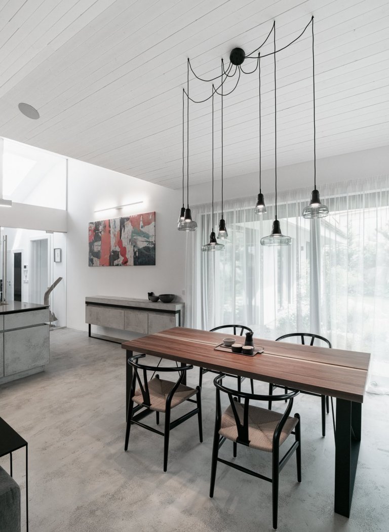 Jídelní stůl jsme umístili do nejsvětlejšího rohu místnosti. Černá ocelová konstrukce je doplněna o stolovou desku z ořechu. 