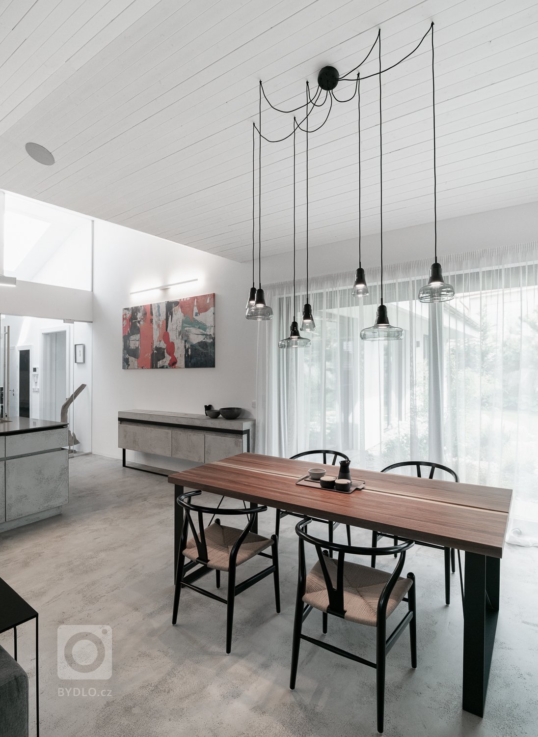 Jídelní stůl jsme umístili do nejsvětlejšího rohu místnosti. Černá ocelová konstrukce je doplněna o stolovou desku z ořechu. 