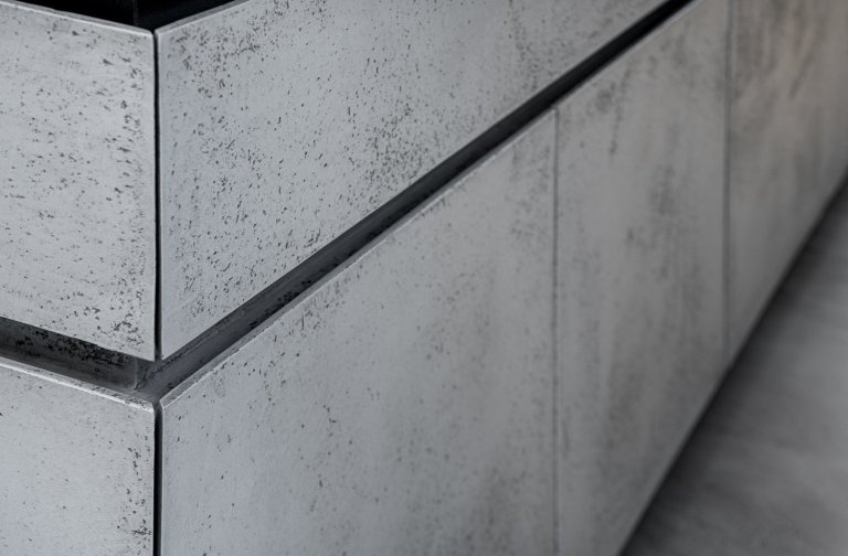 Subtilní pracovní deska je z umělého kamene. Pro zachování čistého designu byla použita kombinace bezúchytkového systému tipon s tichým dojezdem a elektrický systém “servo-drive”. 