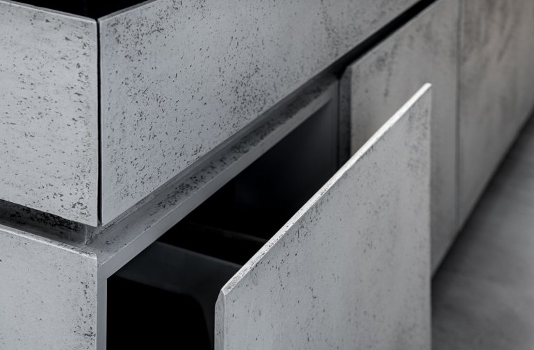 Subtilní pracovní deska je z umělého kamene. Pro zachování čistého designu byla použita kombinace bezúchytkového systému tipon s tichým dojezdem a elektrický systém “servo-drive”. 