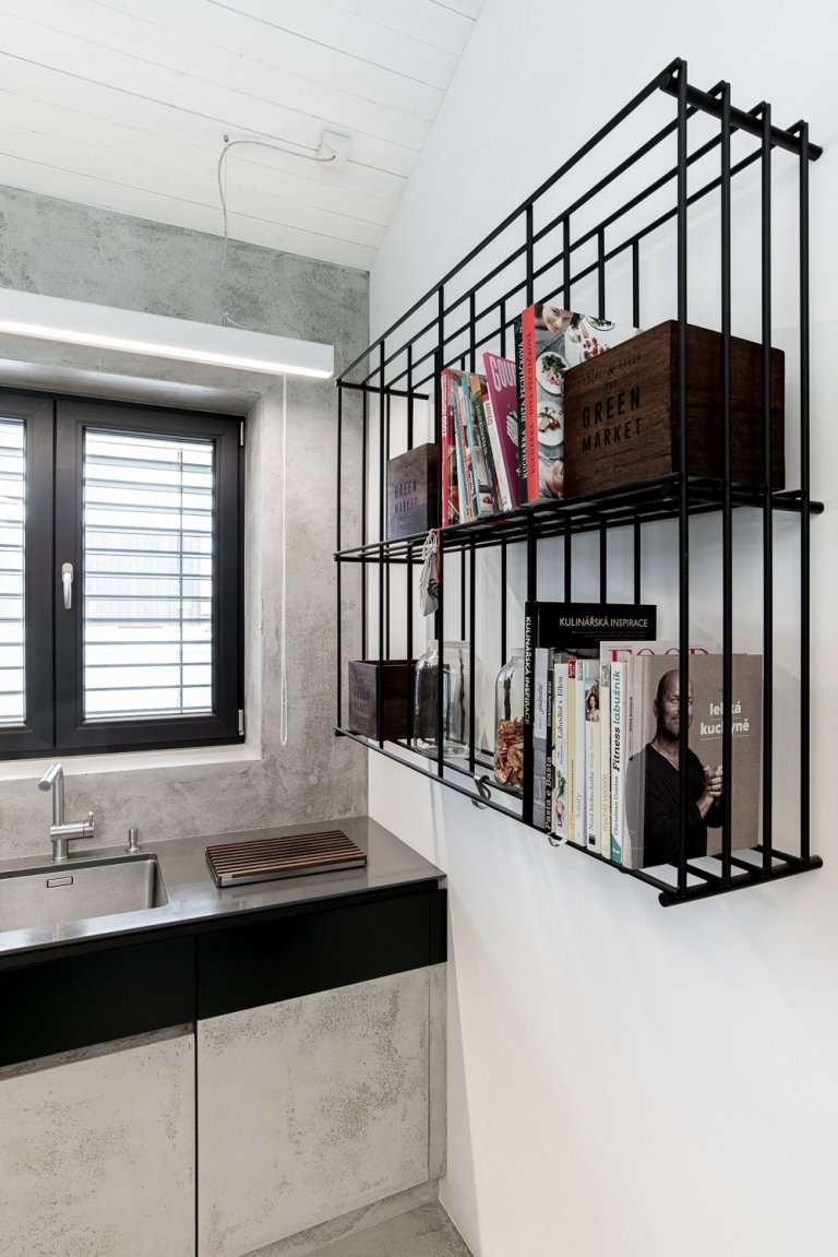 Černá ocelová konstrukce je doplněna o stolovou desku z ořechu. Židle oblého tvaru barevně korespondují se stolem.