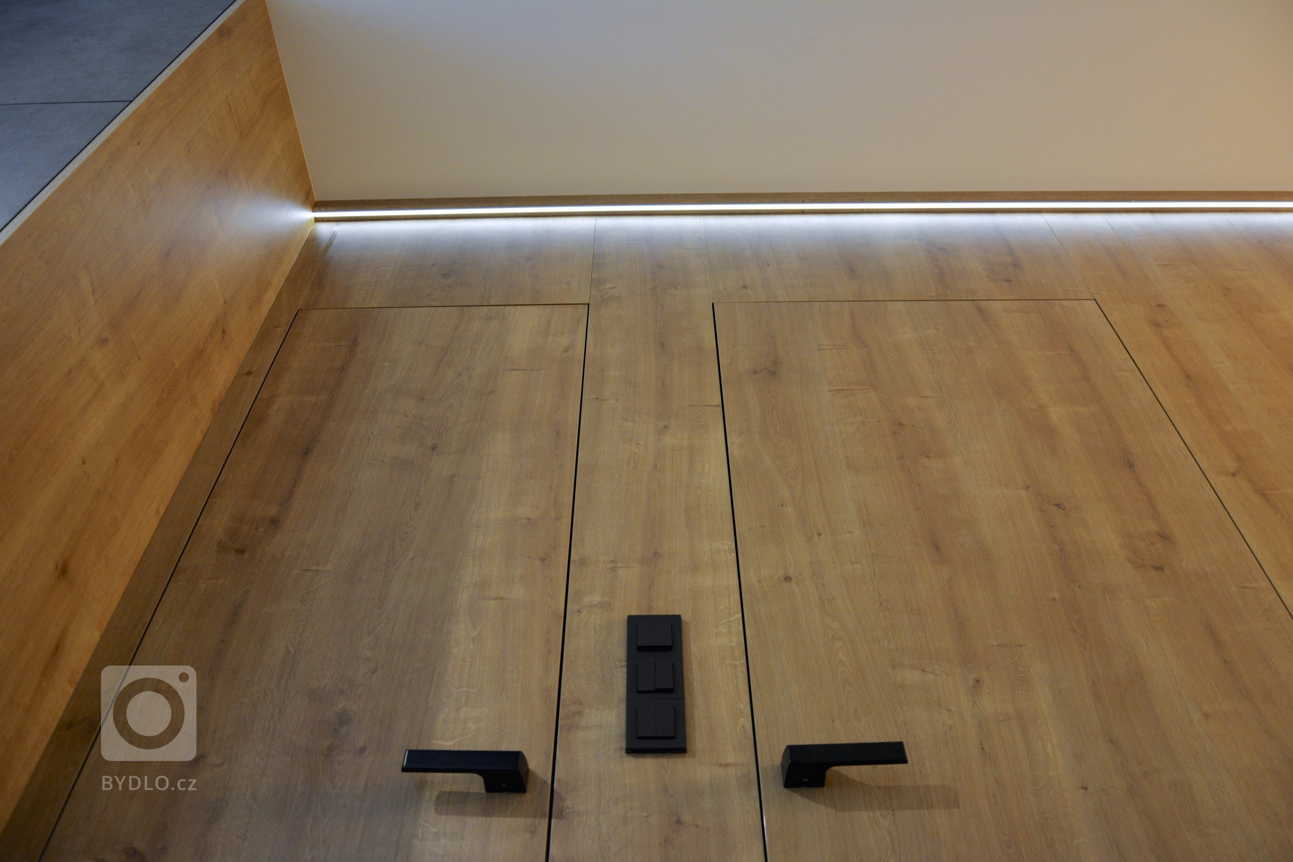 Dnes tu máme praktický interiér. Na kuchyni, jsme použili lamino v dekoru betonu a teplého dubu. Kuchyň plynule navazuje na podsvícené obložení jídelny, ve…