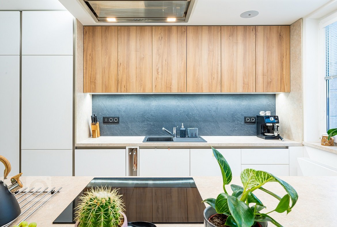 Bílá kuchyň v lakovaném matu PerfectSence je doplněna dekorem ořechu. Dominantou kuchyně je ostrůvek s podsvícenou kamennou dýhou. Interiér je světlý a vzdušný…