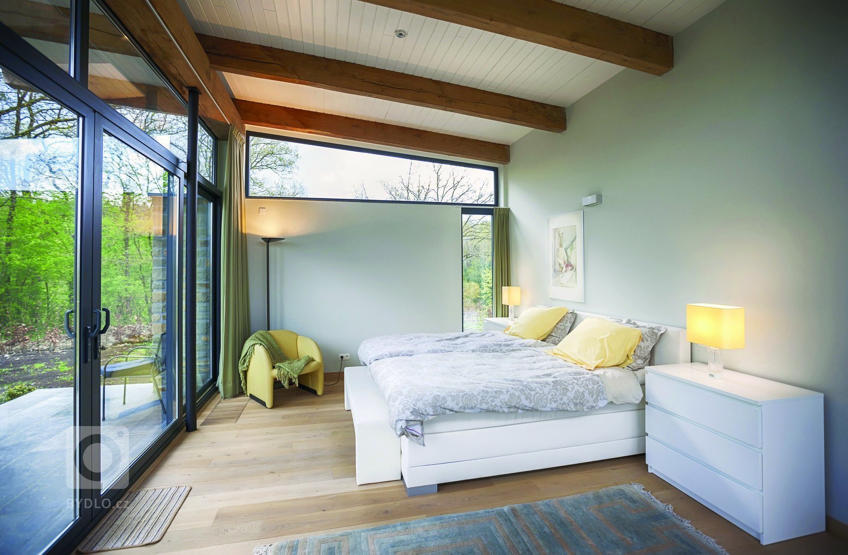 Ložnice s prosklenou zdí a dřevěným stropem.