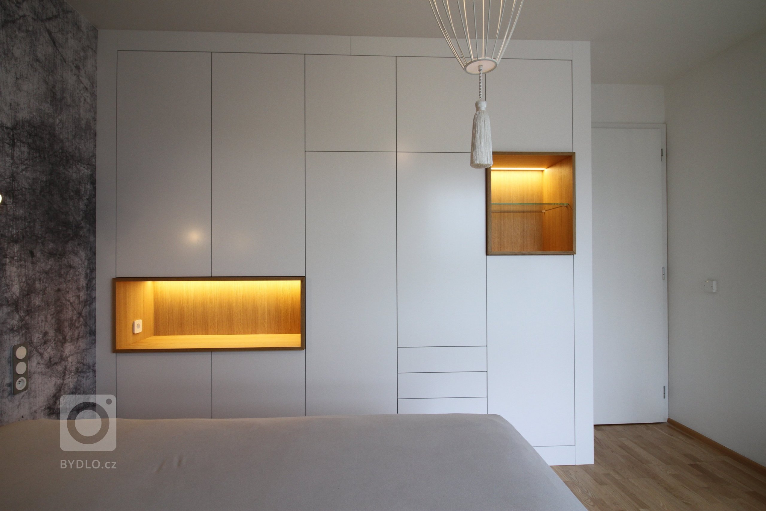 Interiér ložnice s italskou tapetou a svítidly, šatní skříň podle autorského návrhu.
