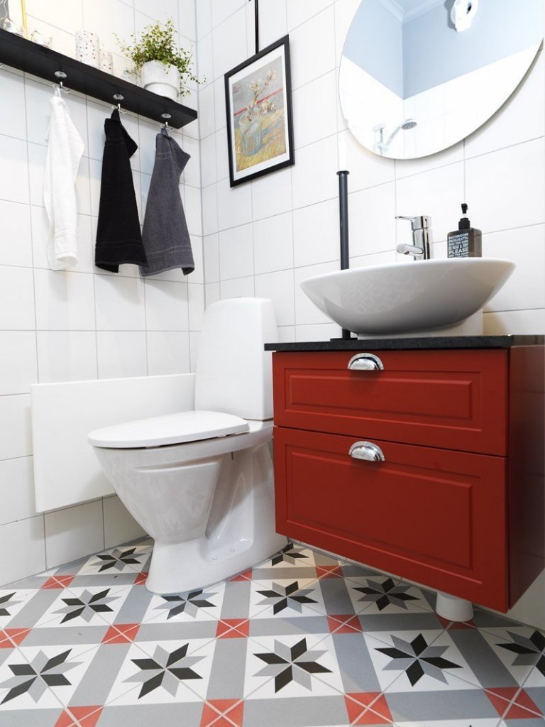 WC s bílými obklady a dlažbou s klasickým historickým vzorem.