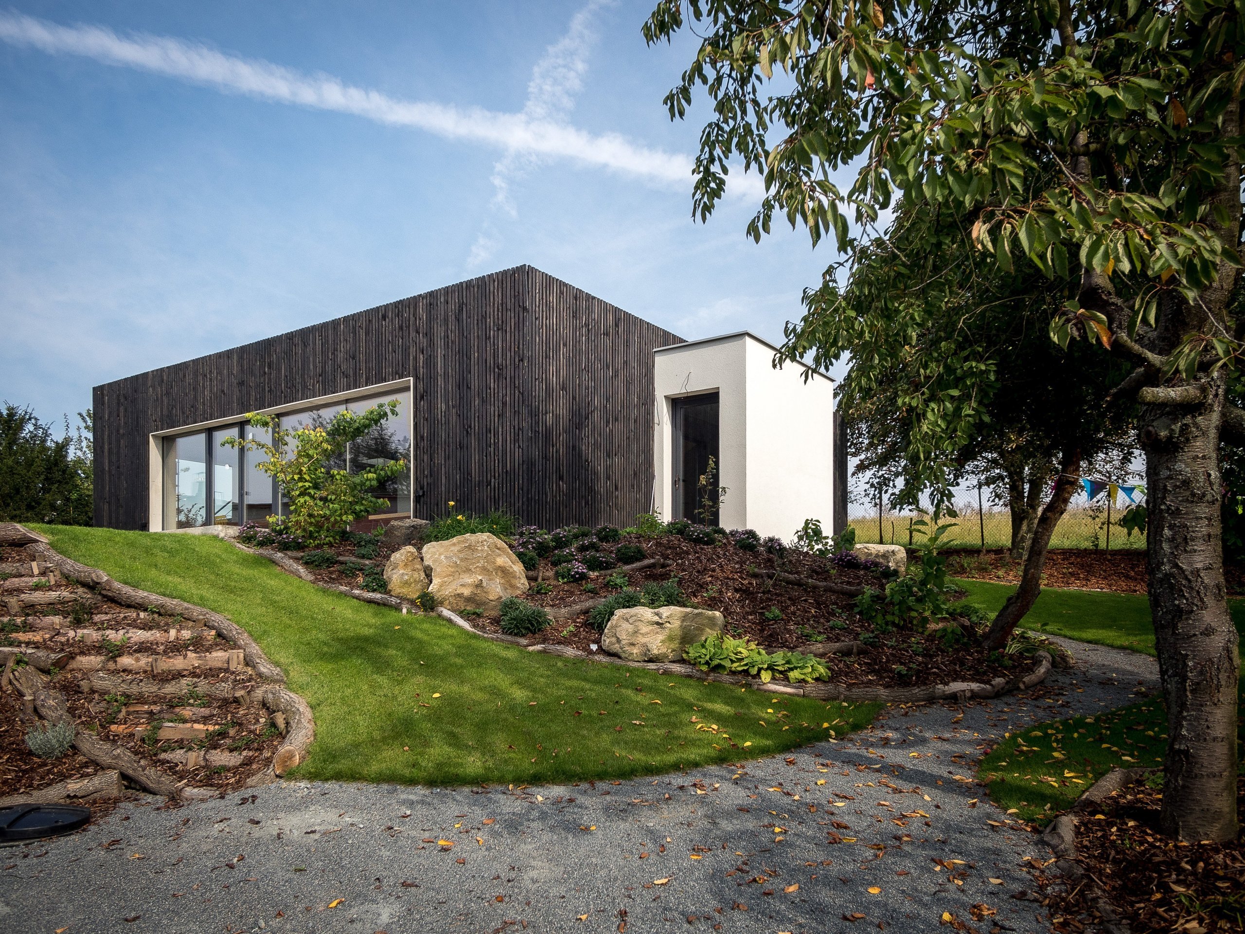 Dům ZEN HOME v podobě kvádru s černou dřevěnou fasádou je doplněn malou přístavbou vstupní haly v bílé omítce. Dům ZEN HOME v podobě kvádru s černou dřevěnou fasádou je doplněn malou přístavbou vstupní haly v bílé omítce.
